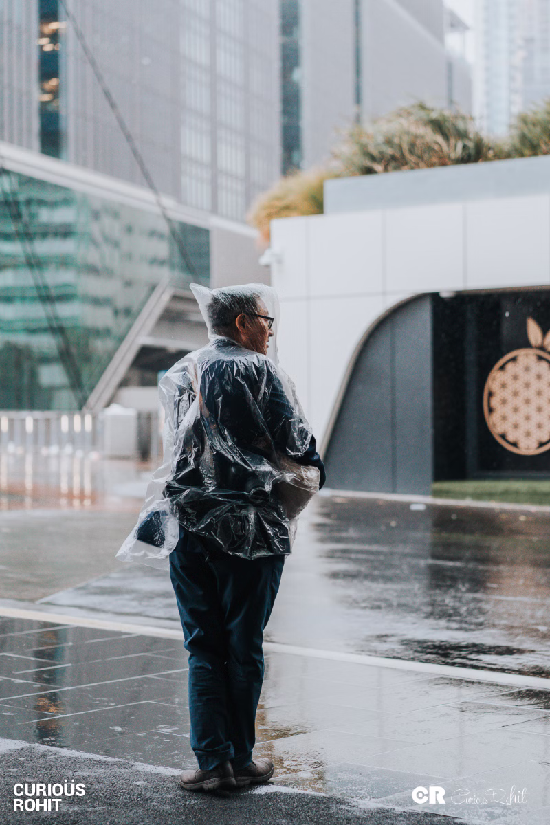 A man wearing a plastic bag on his head standing in the rain