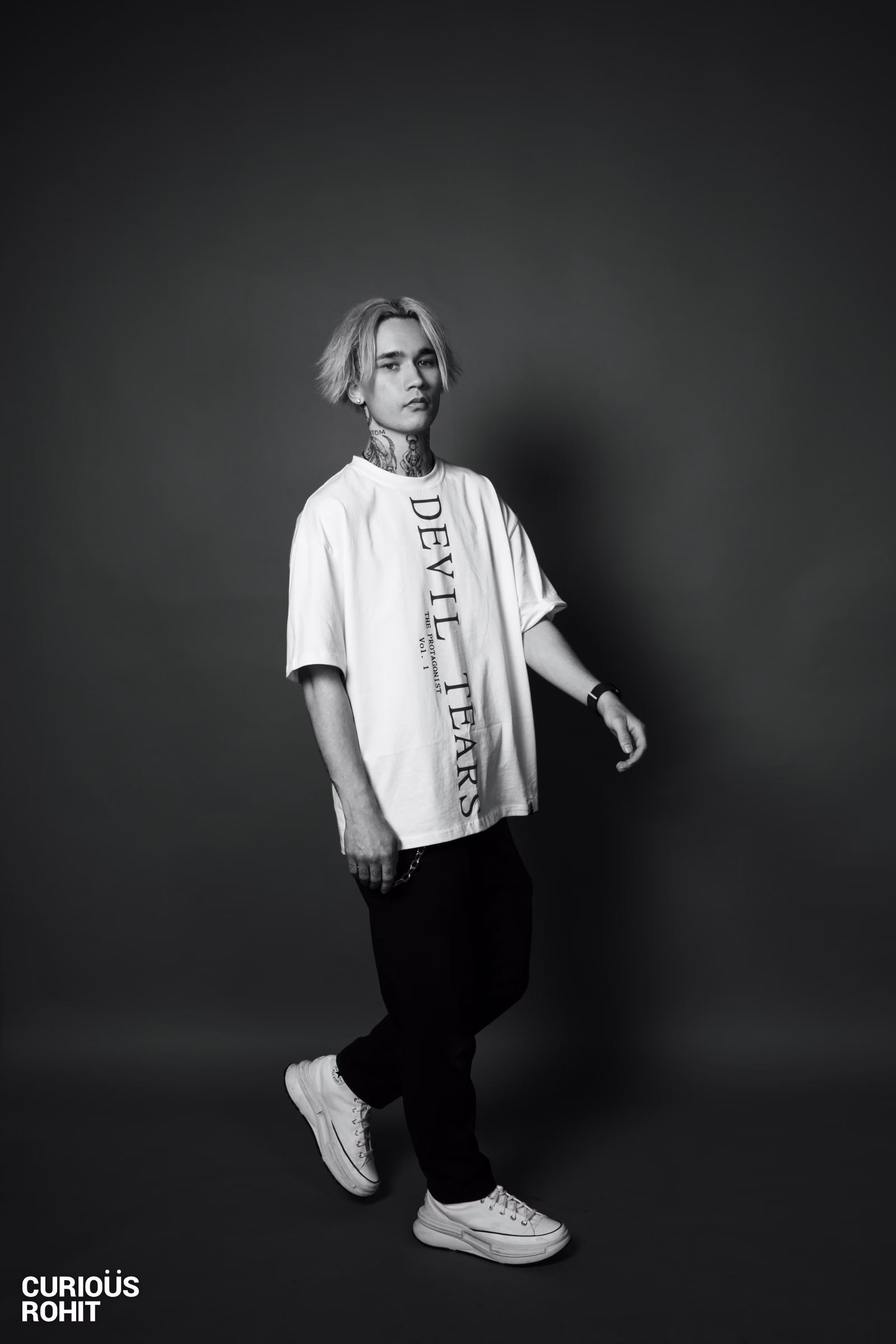 A man wearing a white t-shirt with devil's t-shirt written on it.