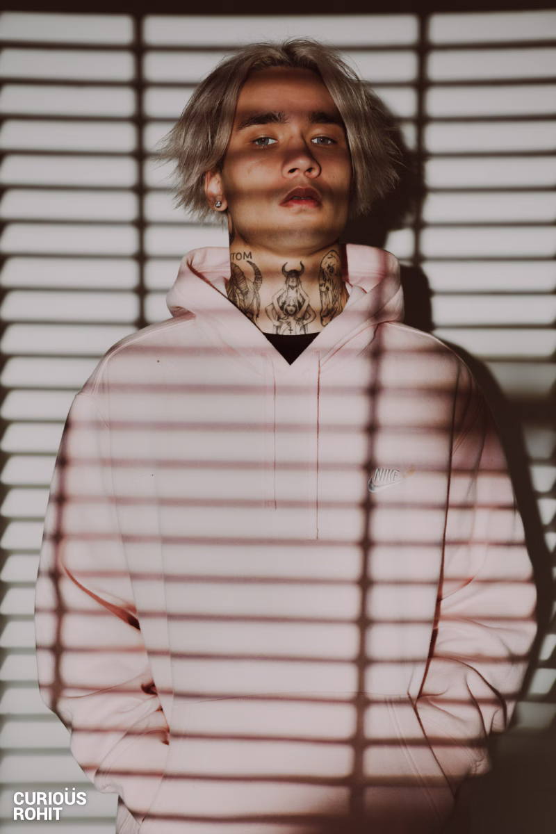 A man with a mohawk and tattoos wearing a pink hoodie